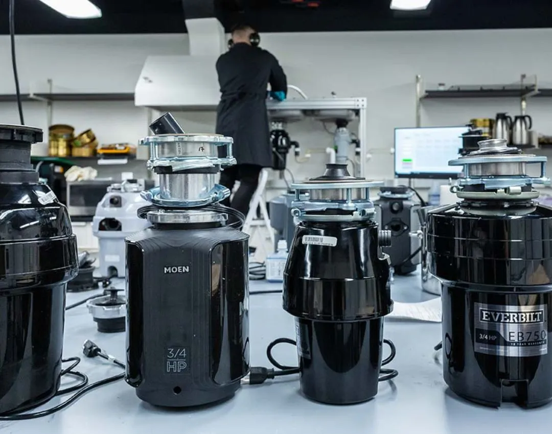 A professional plumber using a red pipe wrench to install a new garbage disposal unit under a kitchen sink in a Columbia, SC home.